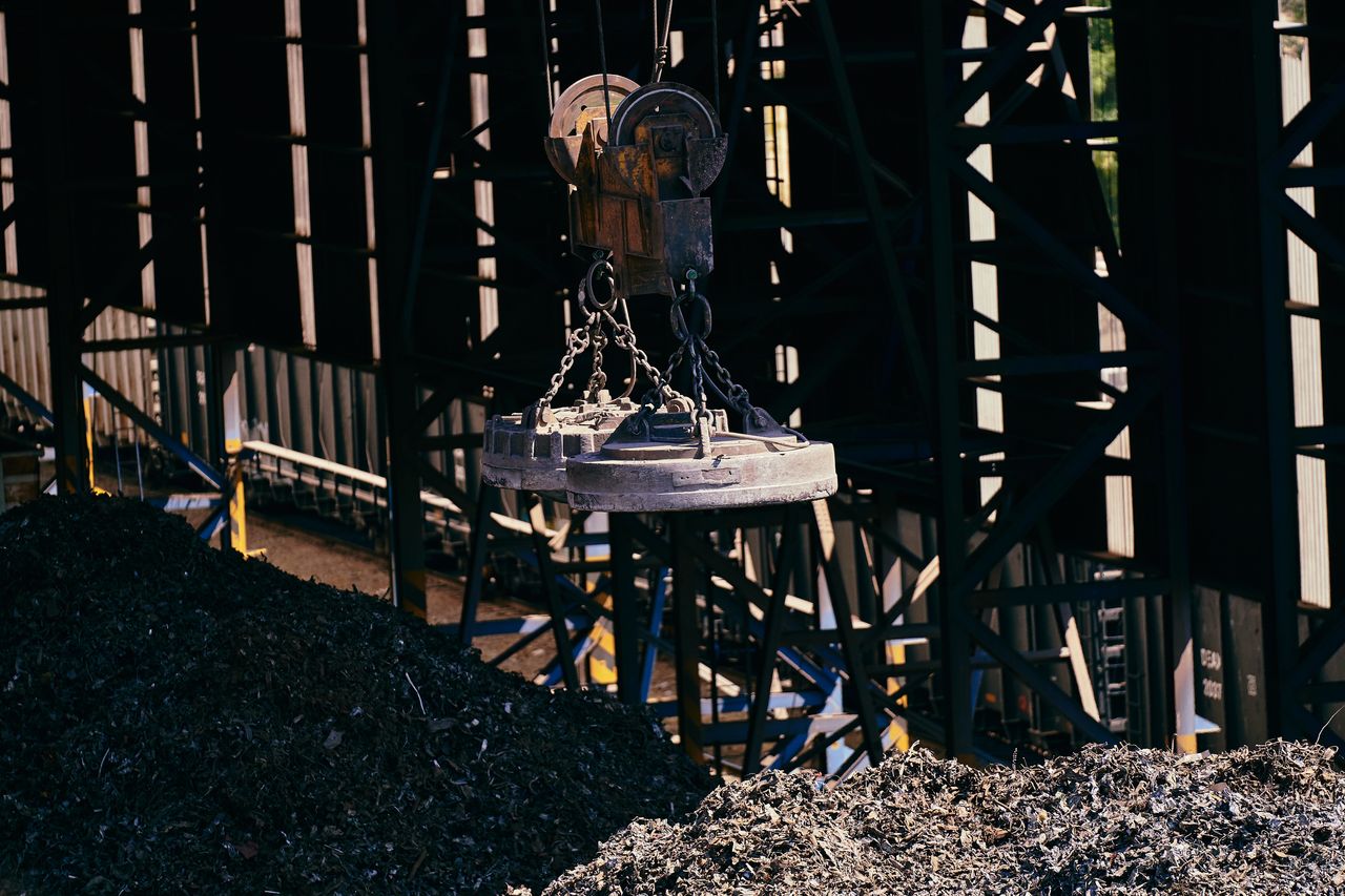 Overhead view of industrial magnet lifting scrap metal in recycling plant.